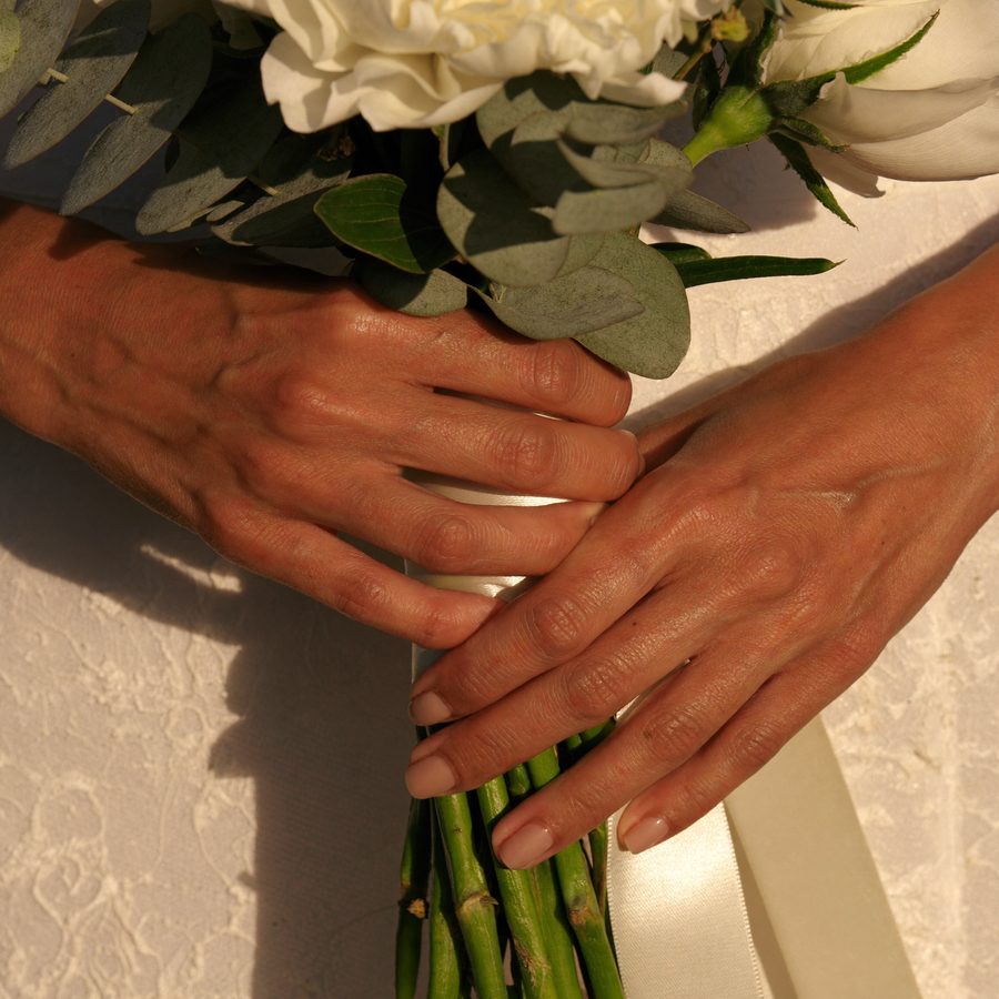 Bridal spray tan: tanned hands holding a bouquet of peonies